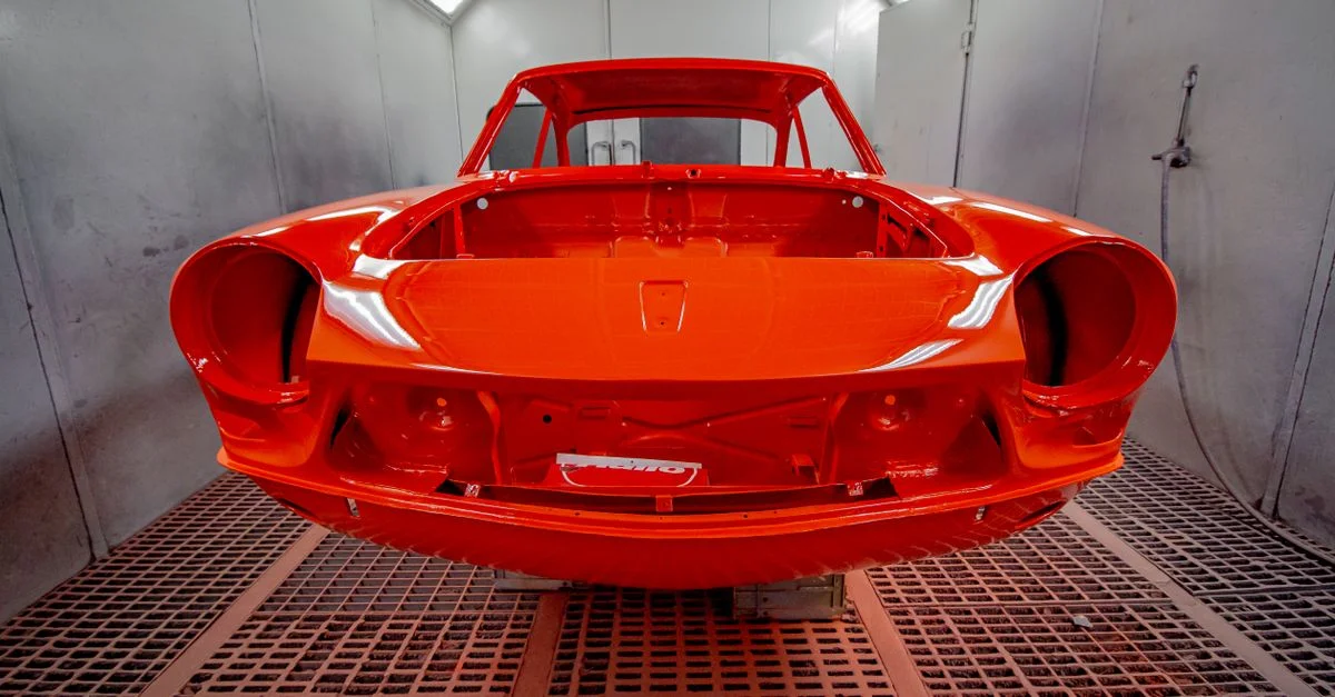 Carrosserie de voiture vivement peinte dans une cabine de peinture industrielle professionnelle.