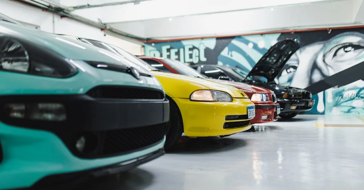 Une gamme de voitures de sport personnalisées exposées dans un garage bien éclairé avec des fresques artistiques.