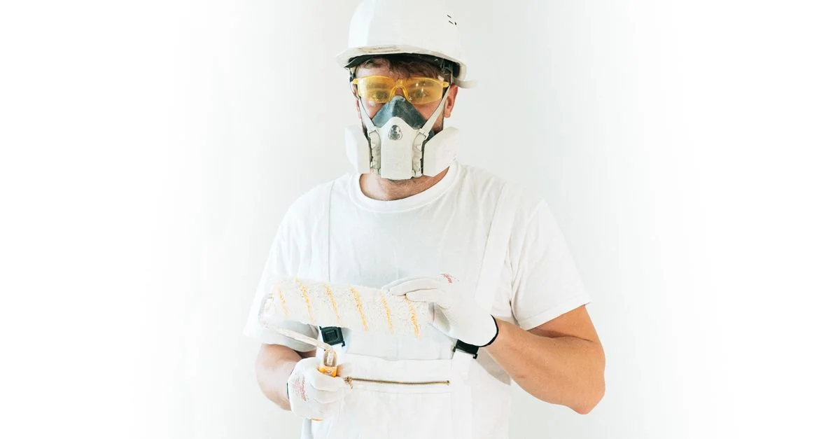Un peintre professionnel portant un équipement de sécurité, tenant un rouleau de peinture, prêt à travailler.