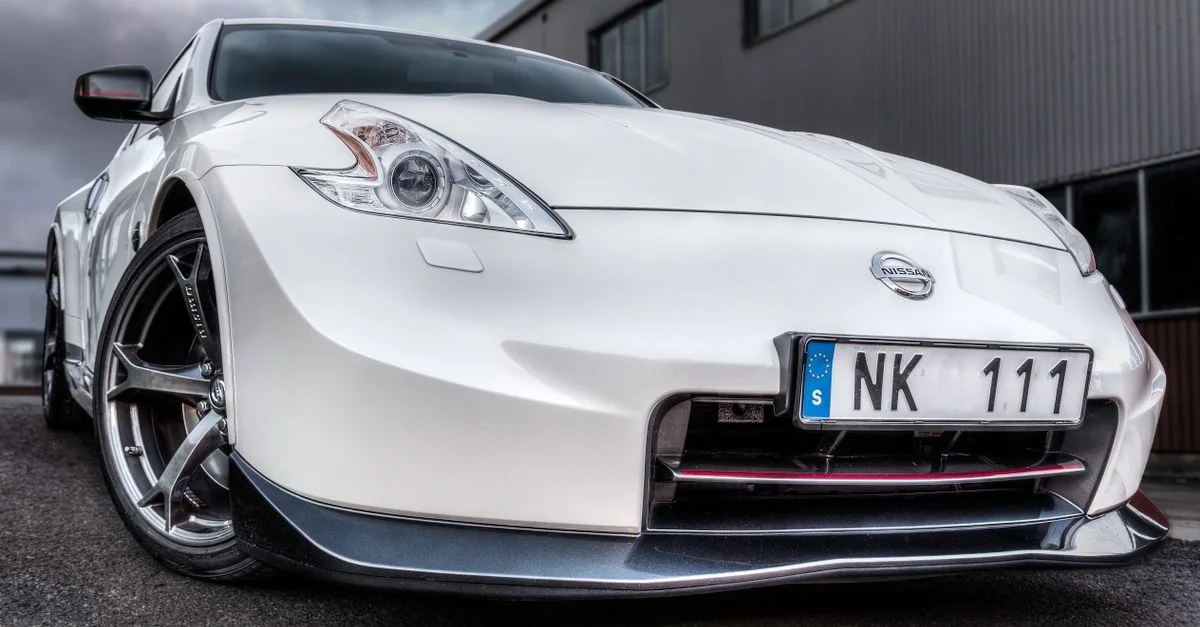 Voiture de sport Nissan blanche capturée d'un angle bas, mettant en valeur son design élégant.
